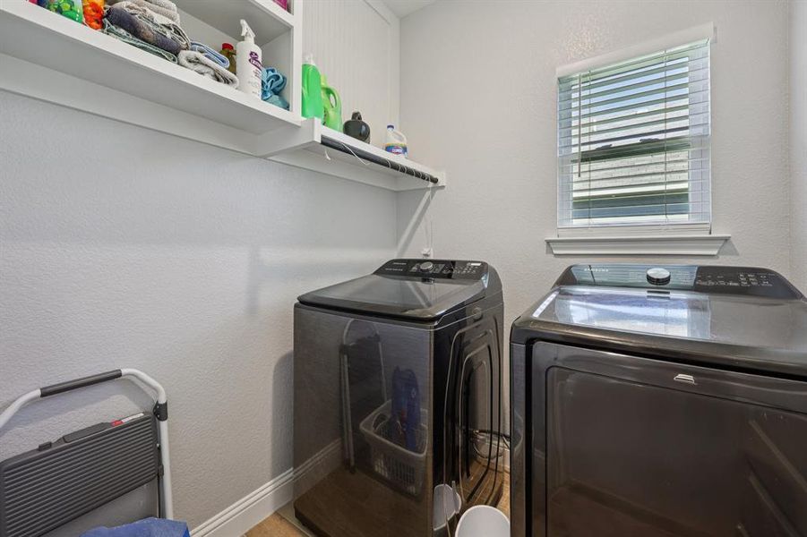 Laundry room with a textured wall, separate washer and dryer, and wood finished floors Laundry room with a textured wall, separate washer and dryer, and wood finished floors
