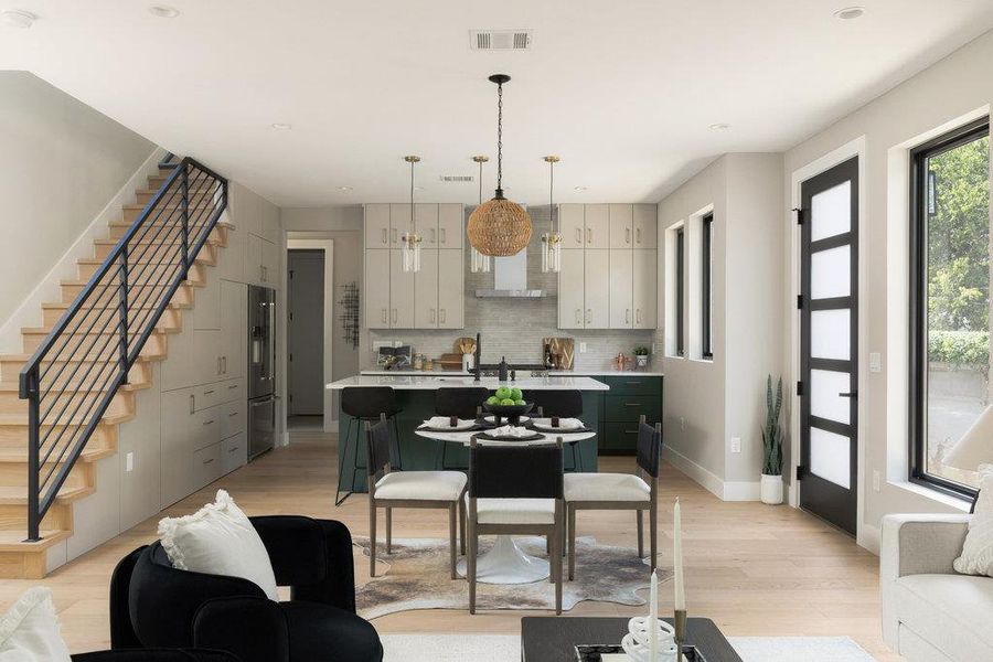 Kitchen featuring a center island with sink, hanging light fixtures, a breakfast bar area, light wood finished floors, and backsplash Kitchen featuring a center island with sink, hanging light fixtures, a breakfast bar area, light wood finished floors, and backsplash