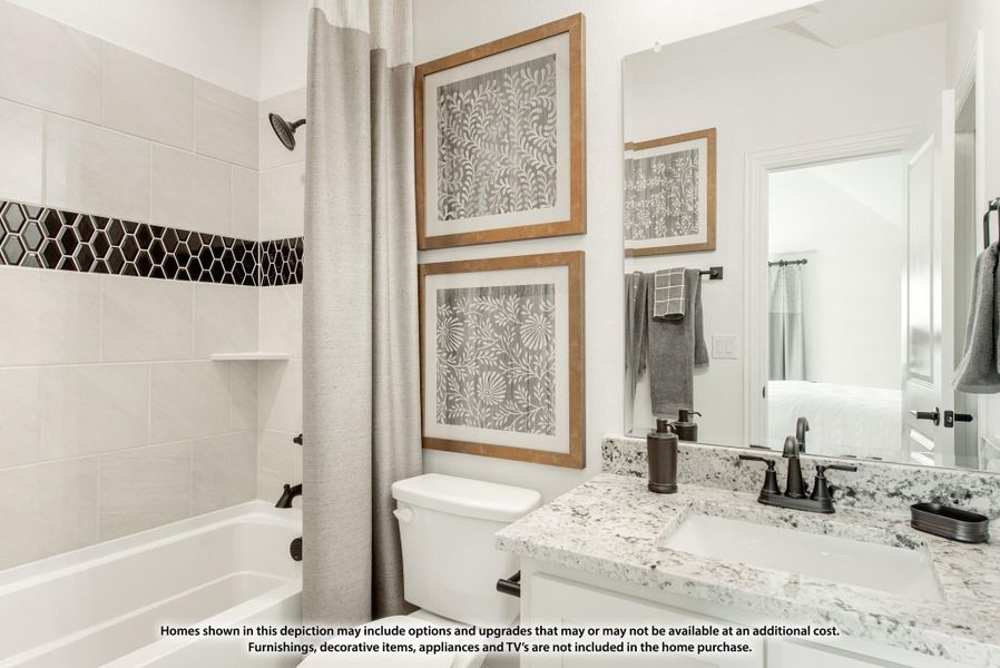 Bathroom with granite countertop, tiled tub-shower with black hex accent, and framed wall art above toilet