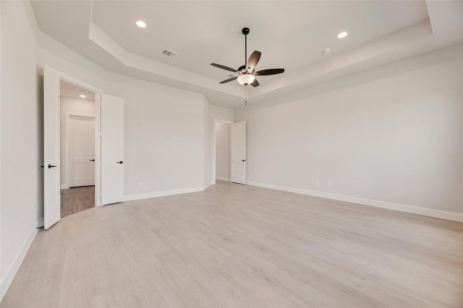 Spare room featuring a raised ceiling, light wood-style floors, recessed lighting, and a ceiling fan