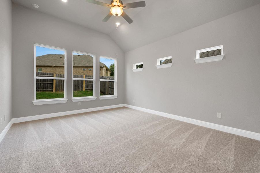 Empty room featuring carpet, ceiling fan, and vaulted ceiling