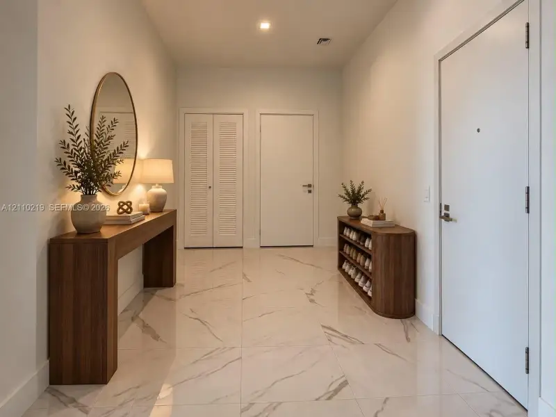 Entryway featuring large-format light-toned flooring with subtle veining, recessed lighting, and white interior doors including louvered closet doors