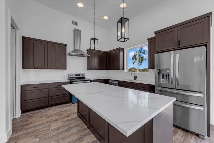Rich dark cabinetry contrasts beautifully with white stone countertops and modern stainless steel appliances.