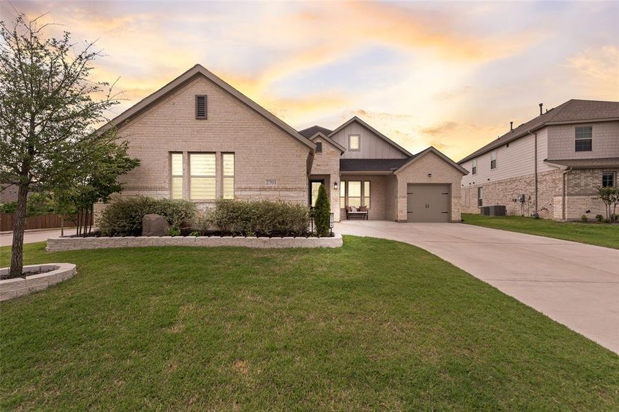 Brick and siding exterior featuring an attached single-car garage, concrete driveway, and mature landscaping
