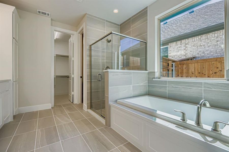 Bathroom with a stall shower, a bath, a spacious closet, and light tile patterned floors