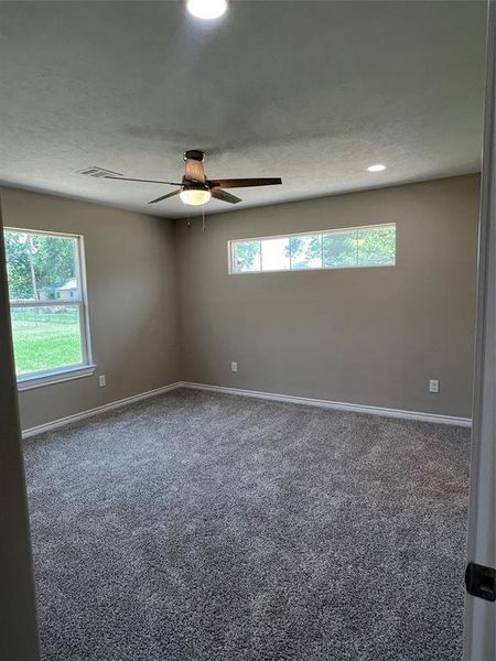 Carpeted spare room featuring baseboards and a ceiling fan
