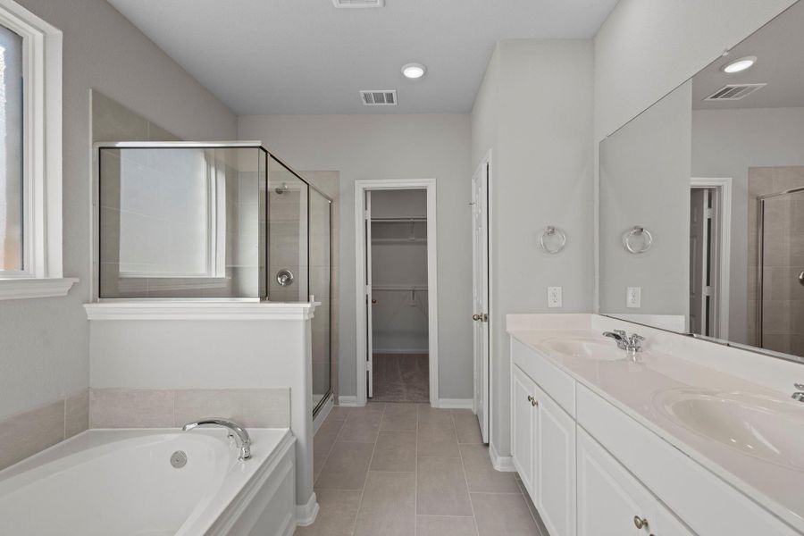 The en-suite bathroom offers a spa-like atmosphere with its elegant design, high end finishes, and tasteful lighting, creating a retreat within your own home.