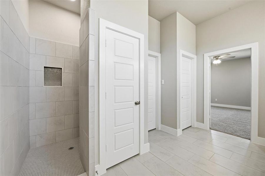 Bathroom featuring a shower stall and a ceiling fan