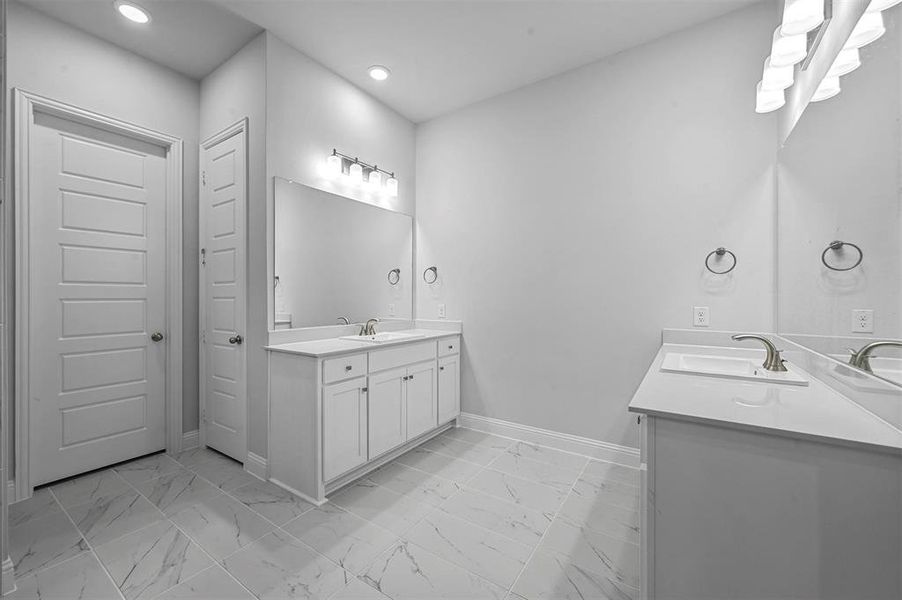 Full bath with two vanities, light marble finish floors, and recessed lighting