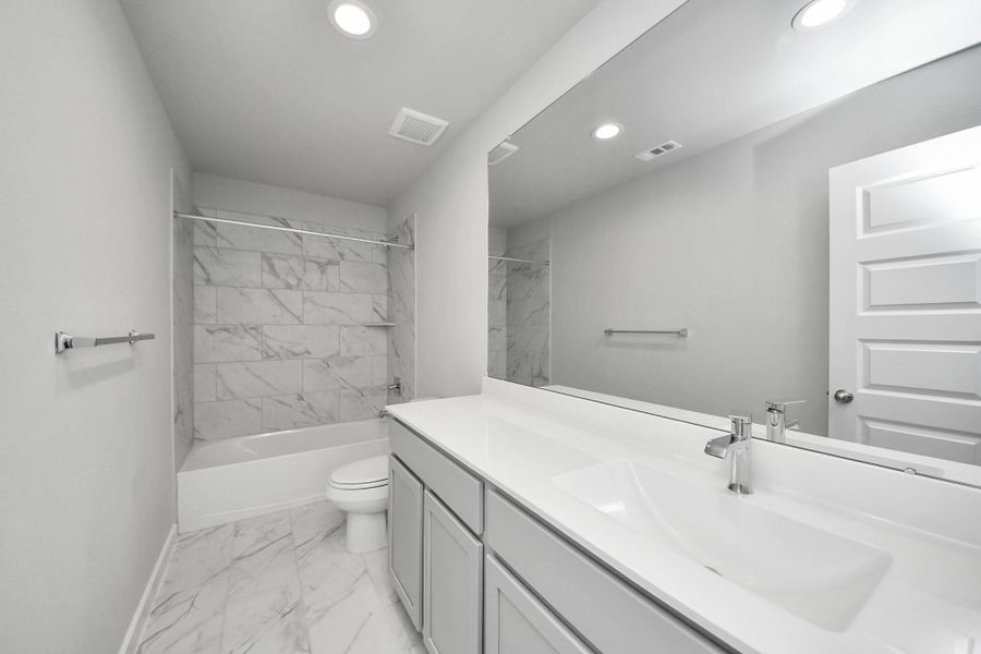 Secondary bath features tile flooring, bath/shower combo with tile surround, light stained wood cabinets, beautiful light countertop. Secondary bath features tile flooring, bath/shower combo with tile surround, light stained wood cabinets, beautiful light countertop.