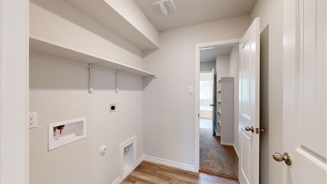 Dedicated utility area featuring wood-finish flooring, white walls, and built-in shelving Dedicated utility area featuring wood-finish flooring, white walls, and built-in shelving