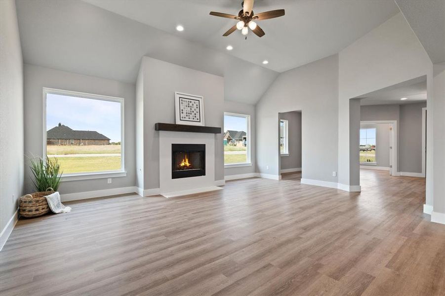 living room with light hardwood / wood-style flooring, vaulted ceiling, ceiling fan, and a healthy amount of sunlight