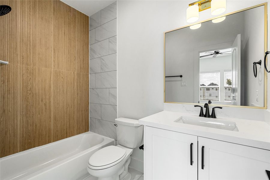 Beautiful en-suite full bathroom located in the third-floor secondary bedroom, featuring modern finishes, a quartz vanity, and a stylish wood-accented shower wall.