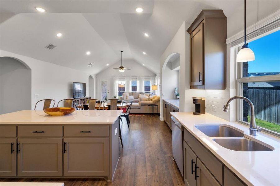 Kitchen featuring ceiling fan, sink, hanging light fixtures, dark hardwood / wood-style flooring, and lofted ceiling