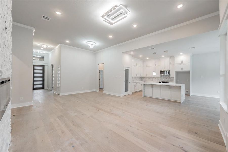 Unfurnished living room with ornamental molding, light wood-style flooring, and recessed lighting