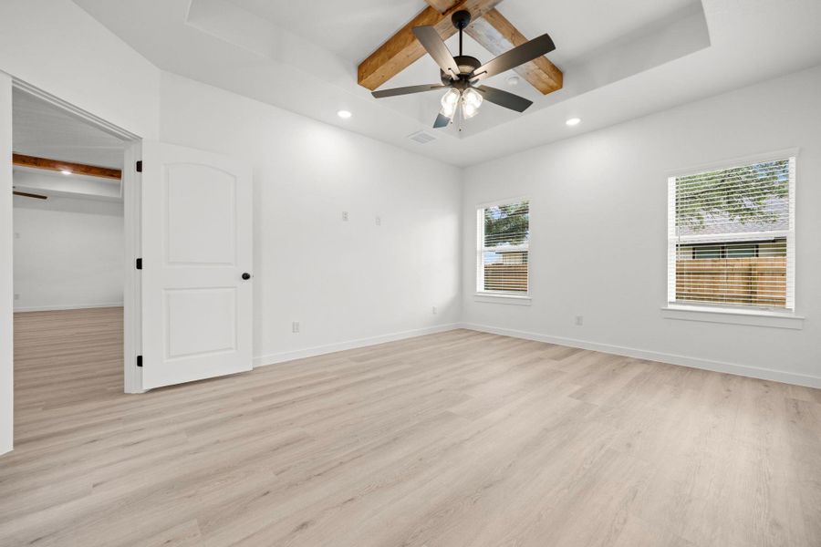 A spacious, naturally illuminated room features light-colored hardwood floors and a ceiling fan with integrated lighting. A spacious, naturally illuminated room features light-colored hardwood floors and a ceiling fan with integrated lighting.