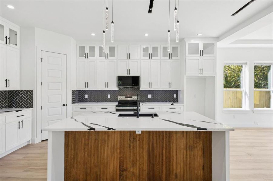 Kitchen featuring light stone counters, white cabinetry, light wood finished floors, appliances with stainless steel finishes, and recessed lighting