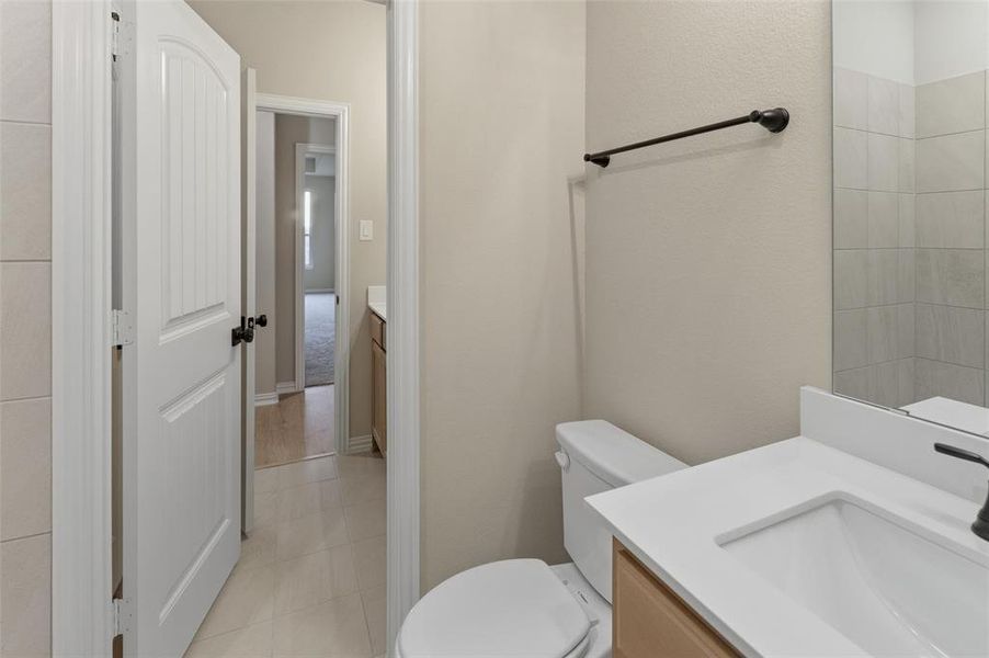 Bathroom featuring a single-sink vanity with a white countertop, under-mount sink, and dark-finish faucet