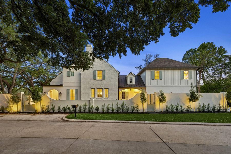 Beautifully illuminated exterior showcasing timeless architecture, gated courtyard walls & professionally designed landscape lighting. Mature trees frame the property while the warm interior glow highlights the inviting presence at dusk.  We love this additional parking space for convenience!