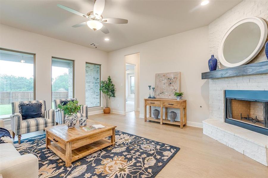 Living room featuring ceiling fan, a fireplace, and light hardwood / wood-style floors