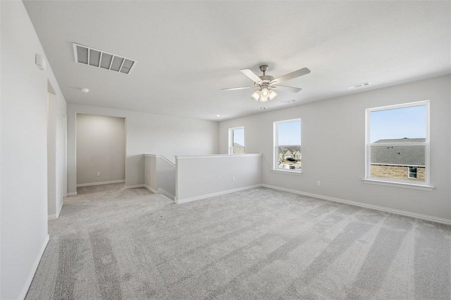 Unfurnished room with light colored carpet and ceiling fan Unfurnished room with light colored carpet and ceiling fan
