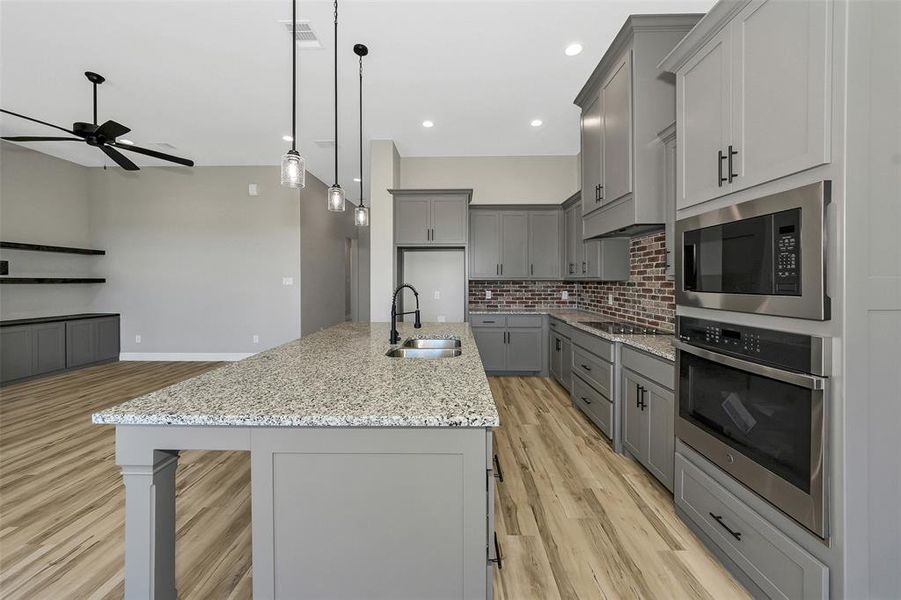 Kitchen featuring gray cabinetry, oven, a ceiling fan, backsplash, and built in microwave