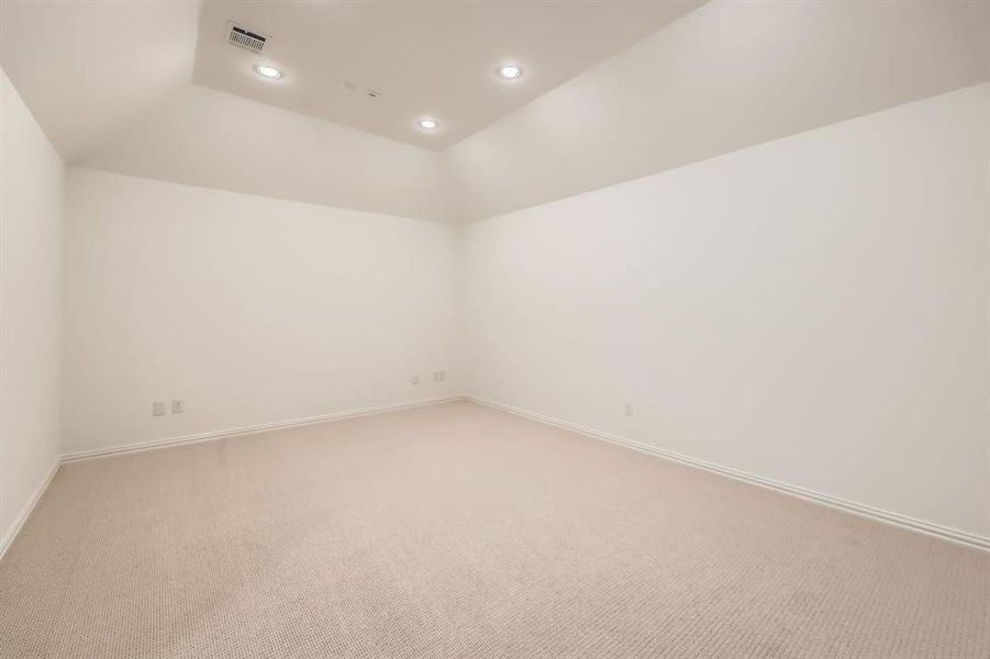 Carpeted empty room featuring vaulted ceiling