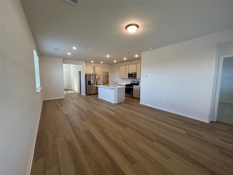 Kitchen with open floor plan, a center island with sink, recessed lighting, stainless steel appliances, and dark wood finished floors Kitchen with open floor plan, a center island with sink, recessed lighting, stainless steel appliances, and dark wood finished floors