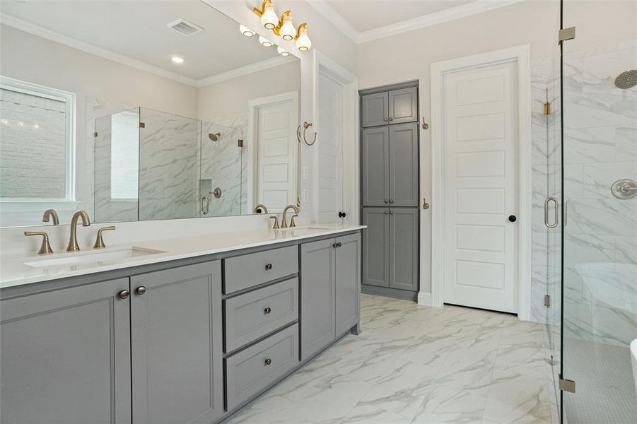 Bathroom with a shower with shower door, dual vanity, tile patterned floors, and crown molding