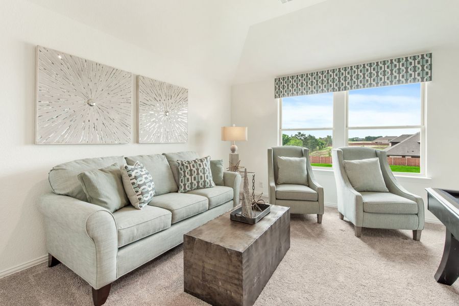 Living room with light gray sofa, two accent chairs, wood coffee table, and large window with outdoor view Living room with light gray sofa, two accent chairs, wood coffee table, and large window with outdoor view