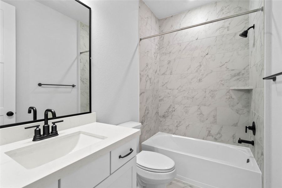 A streamlined secondary bathroom providing a functional tub/shower combination, double sinks, and modern fixtures, seamlessly blending practicality and style. A streamlined secondary bathroom providing a functional tub/shower combination, double sinks, and modern fixtures, seamlessly blending practicality and style.