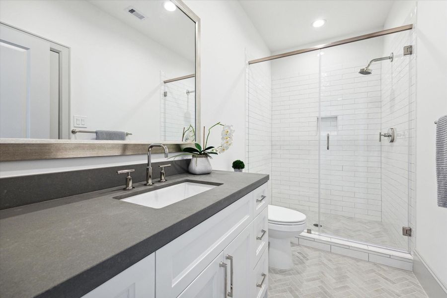 Full bath accessible to game room and secondary bedroom, with Metropolis Gray Quartz countertops and glass enclosed shower.
