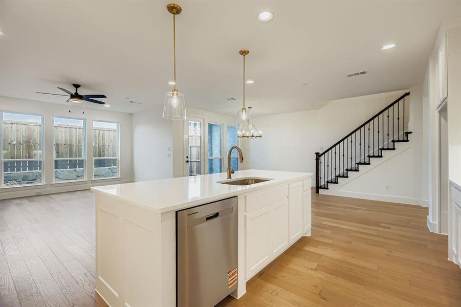 Kitchen with stainless steel dishwasher, white cabinets, light wood-type flooring, recessed lighting, and a center island with sink Kitchen with stainless steel dishwasher, white cabinets, light wood-type flooring, recessed lighting, and a center island with sink
