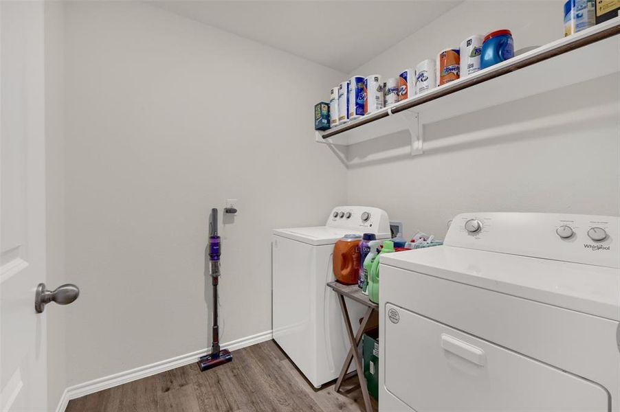 Washroom with baseboards, washer and dryer, laundry area, and wood finished floors