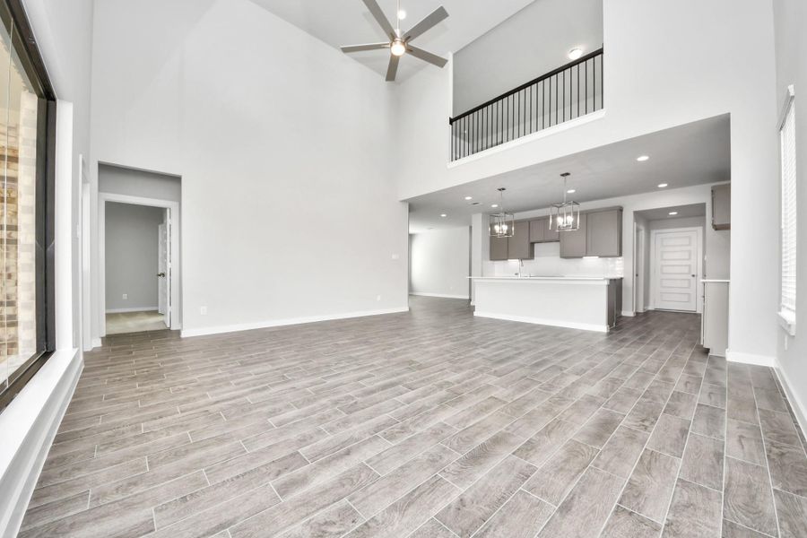Relax and unwind in this inviting family room, illuminated by abundant natural light streaming in through tall windows, complemented by high ceilings and stunning flooring. Stay comfortable year-round with the gentle breeze from the ceiling fan, creating the perfect atmosphere for family gatherings.