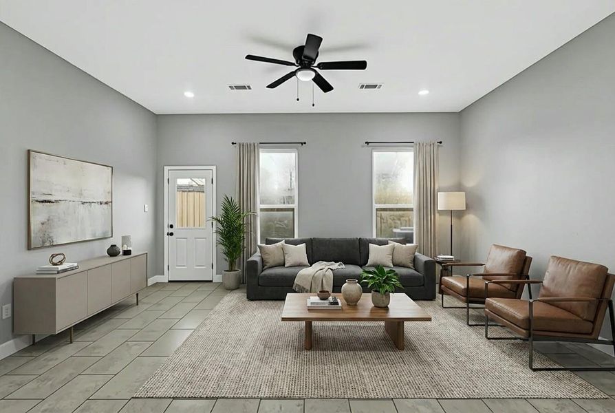 This spacious living room features a modern design with neutral tones, a comfortable gray sofa, and two leather chairs. Large windows provide ample natural light, complemented by a ceiling fan and recessed lighting. A tasteful rug and stylish decor complete the inviting ambiance.