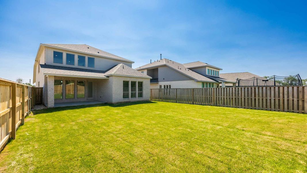 Rear view of house featuring a patio area, a fenced backyard, brick siding, and roof with shingles