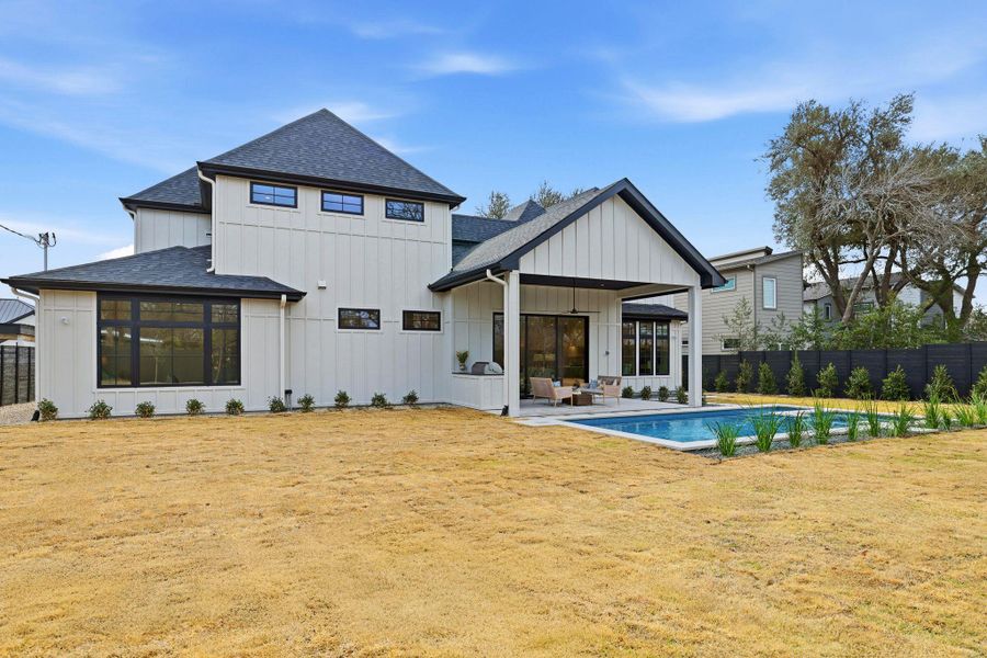 Back of house featuring roof with shingles, board and batten siding, and a patio area
