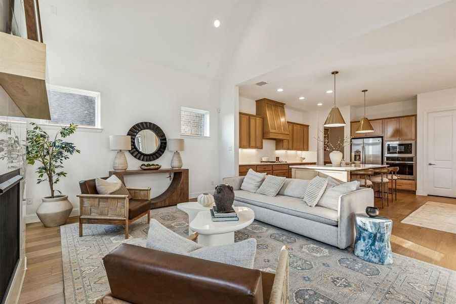 Living area featuring light wood-style flooring, recessed lighting, a fireplace, and a high ceiling
