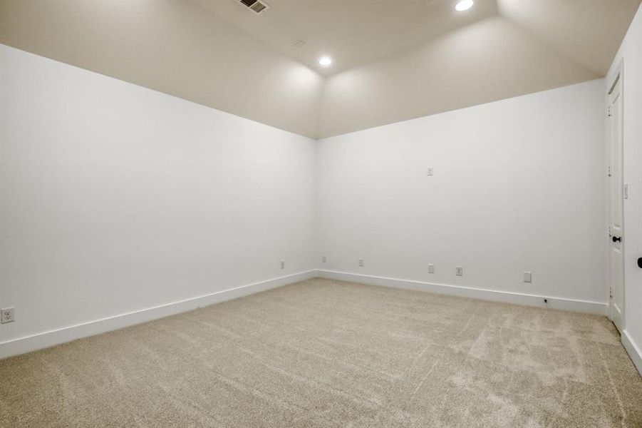 Empty room with lofted ceiling, light carpet, and recessed lighting