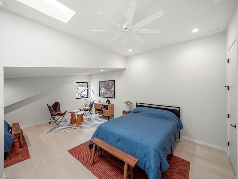 Bedroom with a skylight, light wood-style floors, ceiling fan, and recessed lighting
