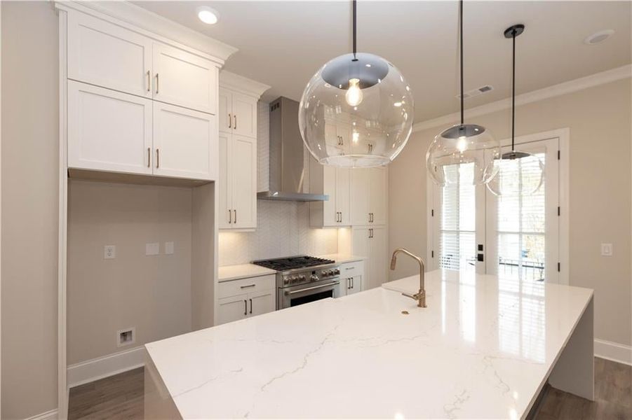 Decorative Aged Iron pendant lights illuminate the Inverness Frost Gloss Quartz waterfall island with extras storage cabinets.