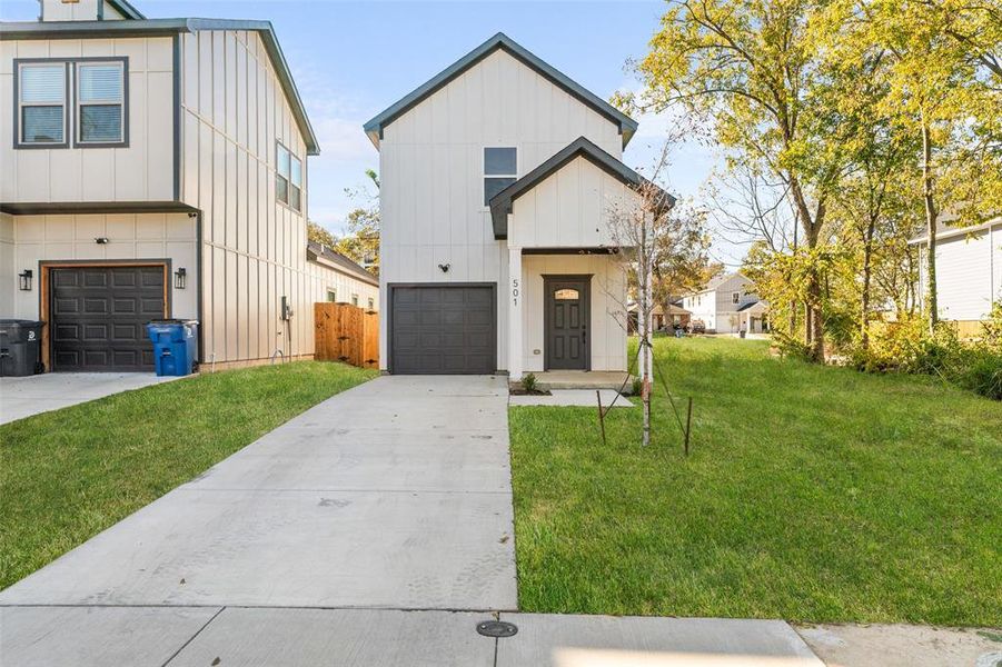 Traditional style home with modern design featuring board and batten siding, concrete driveway, an attached garage, and a front lawn Traditional style home with modern design featuring board and batten siding, concrete driveway, an attached garage, and a front lawn