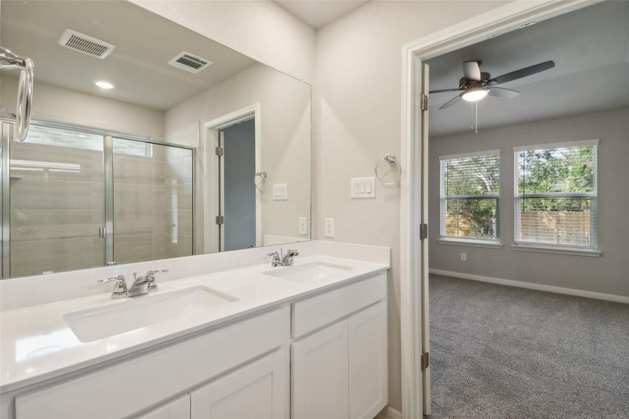 Bathroom with a stall shower, double vanity, a ceiling fan, and baseboards Bathroom with a stall shower, double vanity, a ceiling fan, and baseboards