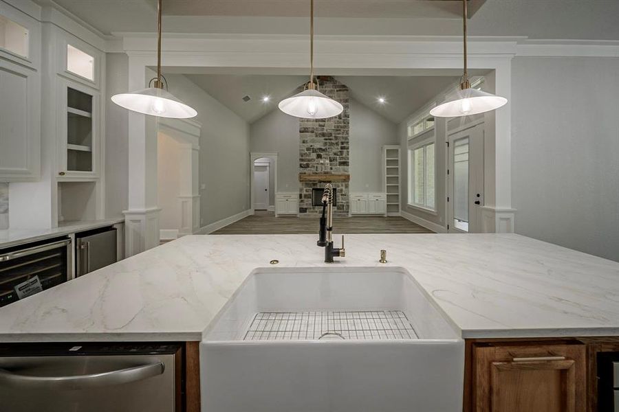 Kitchen featuring light stone counters, appliances with stainless steel finishes, hanging light fixtures, wine cooler, and lofted ceiling Kitchen featuring light stone counters, appliances with stainless steel finishes, hanging light fixtures, wine cooler, and lofted ceiling