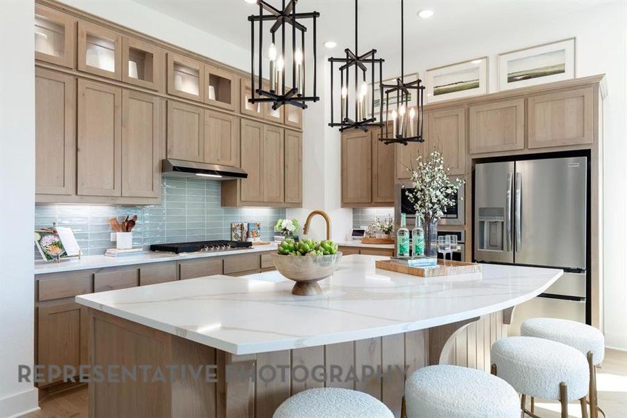 Kitchen featuring decorative backsplash, an island with sink, light wood finished floors, stainless steel fridge, and light stone countertops