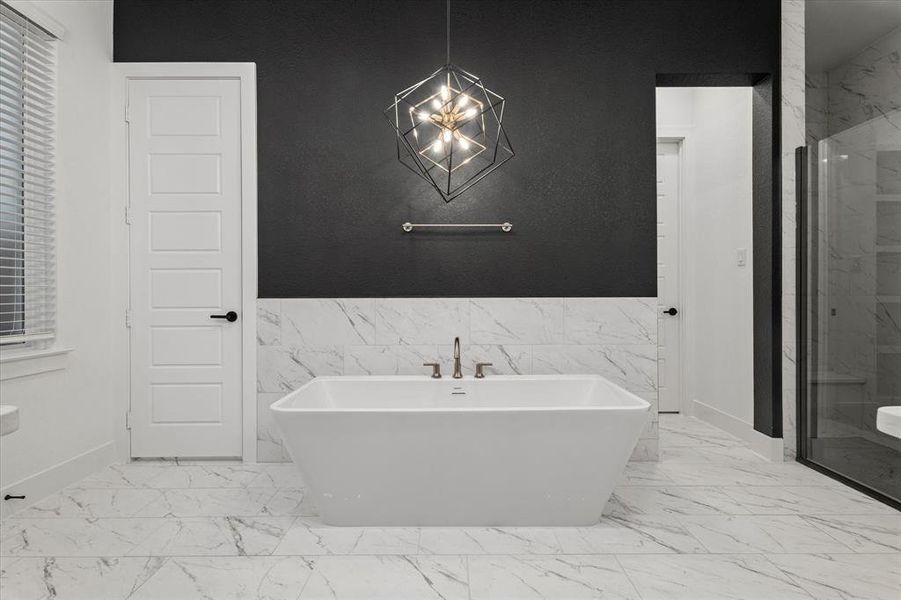 Full bathroom with a marble finish shower, a freestanding tub, tile walls, light marble finish floors, and a wainscoted wall Full bathroom with a marble finish shower, a freestanding tub, tile walls, light marble finish floors, and a wainscoted wall