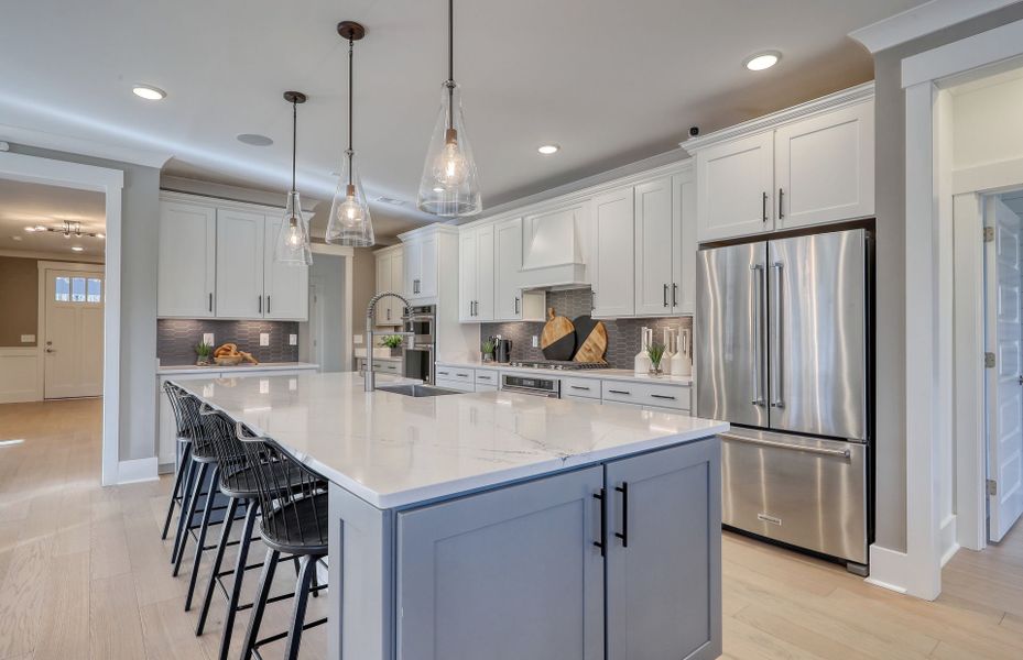 The expansive open Kitchen thoughtfully designed to offer ample seating options. Model Home Representation.