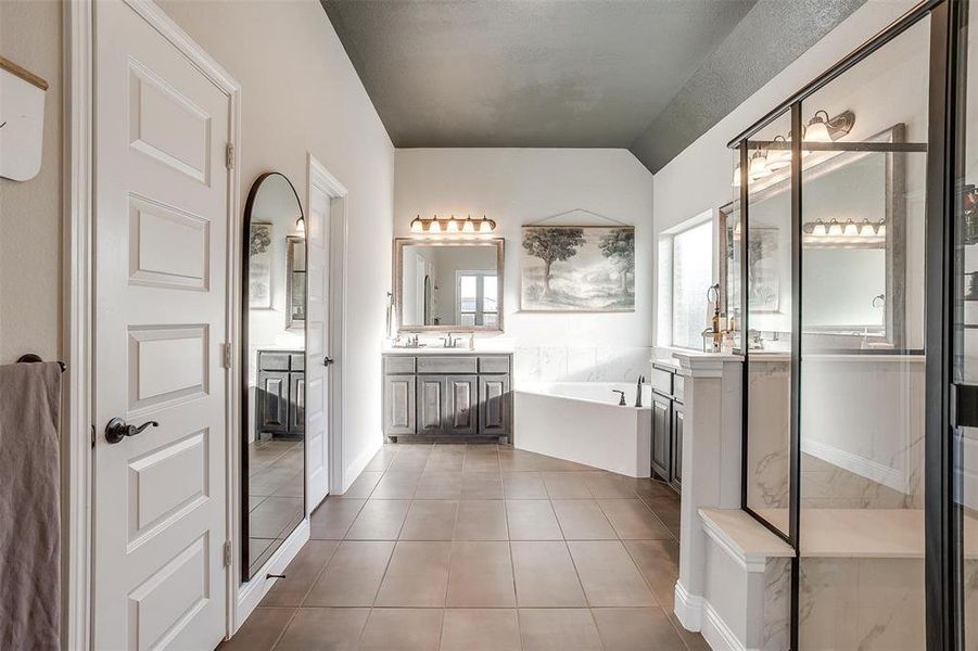 Bathroom featuring tile patterned flooring, vanity, vaulted ceiling, and independent shower and bath