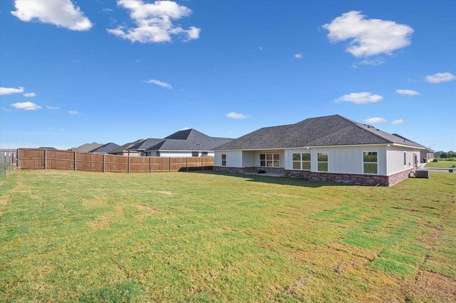 Rear view of property with a patio, a fenced backyard, a shingled roof, and brick siding